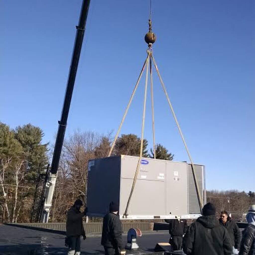 Technicians guiding HVAC unit on a crane