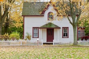 White house with red trim in rural setting with white fence