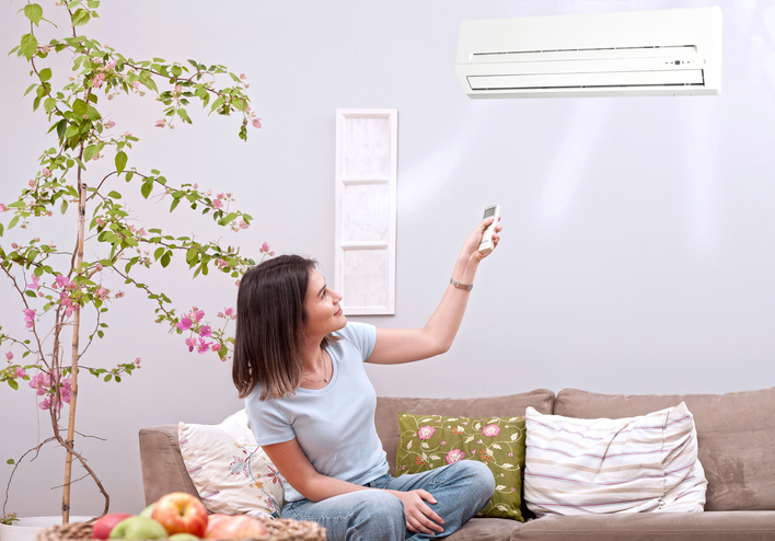 Woman with remote aimed at ductless wall unit