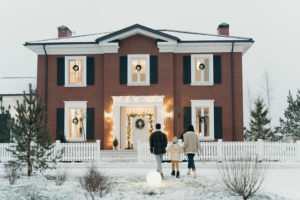 family walking to a home decorated for the holidays during winter