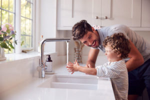 man helps child wash hands at sink