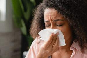 woman sneezing into a tissue as a result of fall allergies