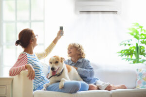 Family sits on couch with mother adjusting ductless unit with remote
