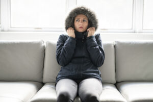 Cold woman on the sofa at home with winter coat