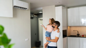 Father with daughter turn on air conditioner using remote control.