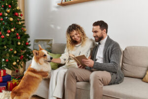 A cozy Christmas celebration with a couple and their adorable corgi by the tree